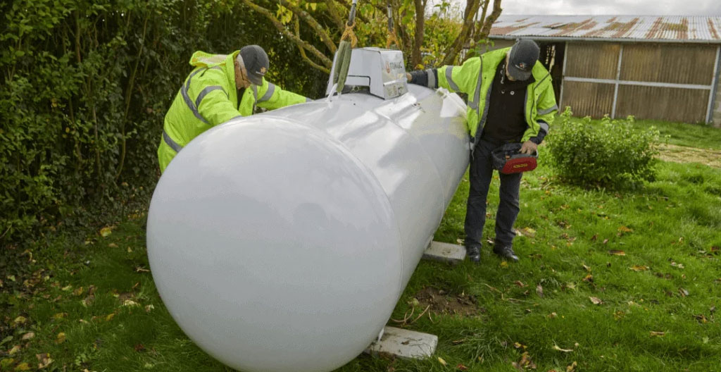 Responsable technique d'une PME vérifiant la jauge connectée d'une citerne de propane sur son site d'activité